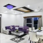 Elegant living room with modern decor, featuring a purple sofa and chic dining area.