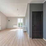Spacious empty room with wooden flooring and large windows for ample natural light.